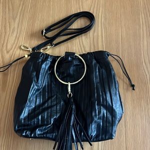 Cinch faux leather cross body purse with gold ring and tassel.